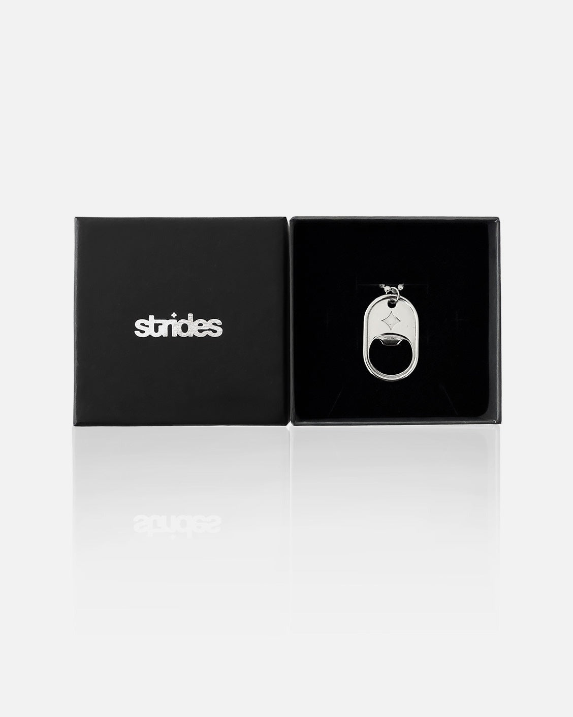 Silver bottle opener with butterfly design on a black 'strides' branded box.