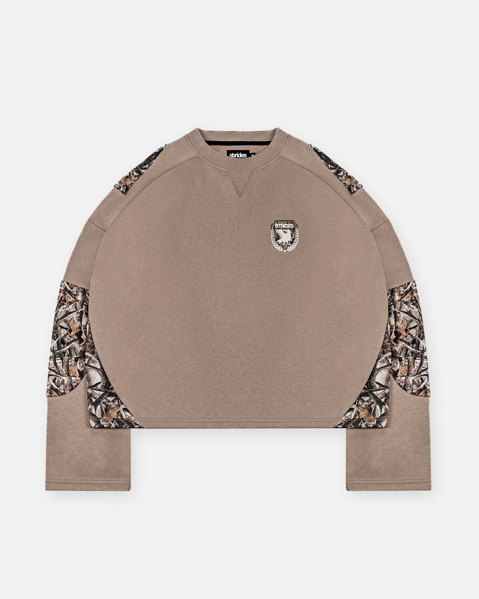 A brown longsleeve unisex top with camouflage patches on the sleeves and a logo print on the chest.