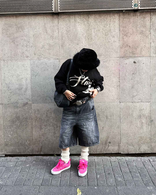 Against a concrete wall, wearing the Echoes Knit Sweater in black