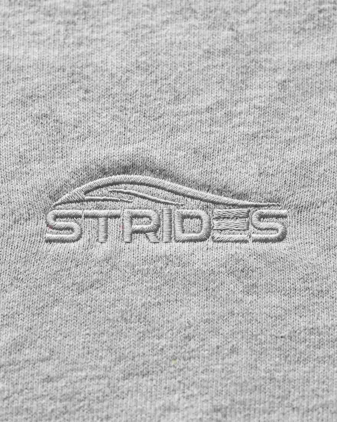 Close-up of the tonal embroidered Strides logo on the grey slim tee