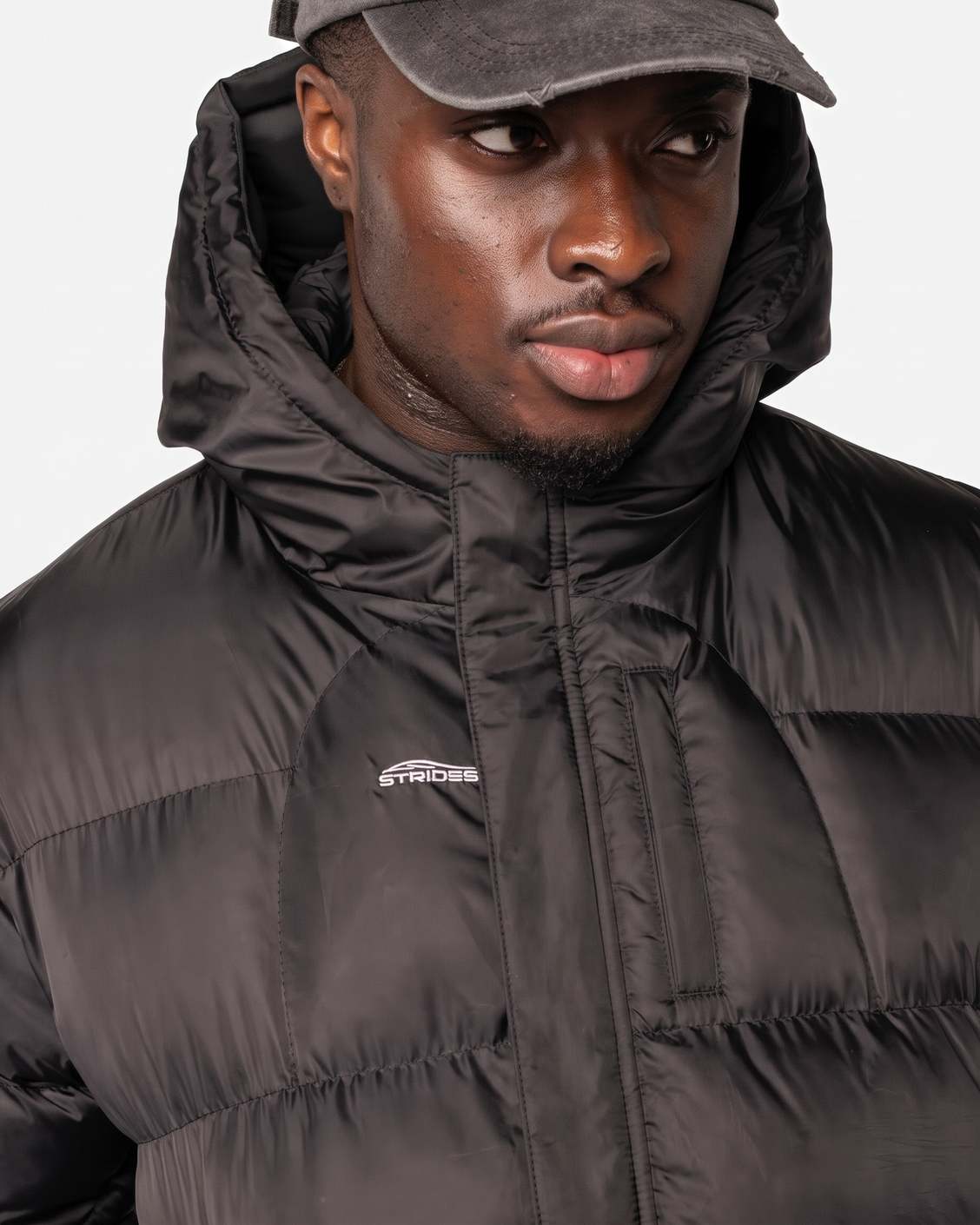 Detail zapínání pod légou proti větru na Apex Puffer Black a reflexního loga Strides na hrudi