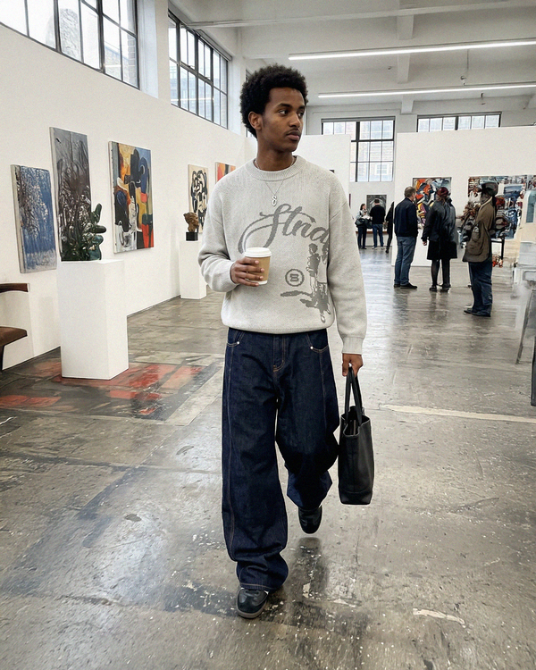 In a gallery, wearing the Echoes Knit Sweater in light grey