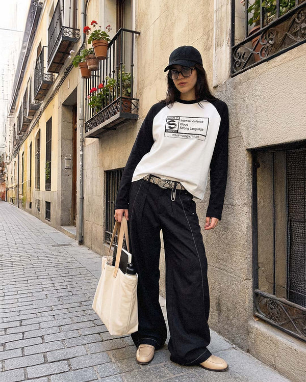 On a Paris side street, wearing the Explicit Raglan Longsleeve with wide black jeans