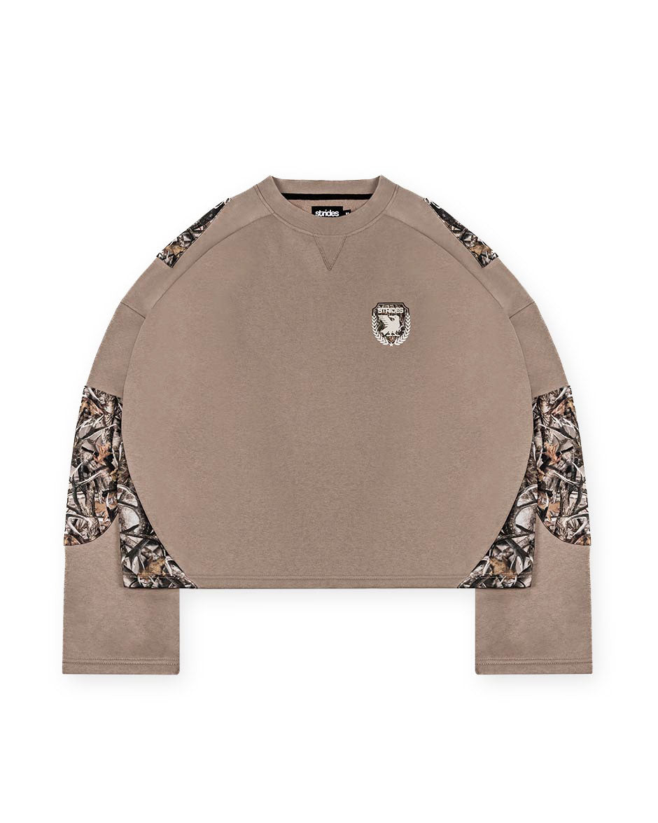 A brown longsleeve unisex top with camouflage patches on the sleeves and a logo print on the chest.