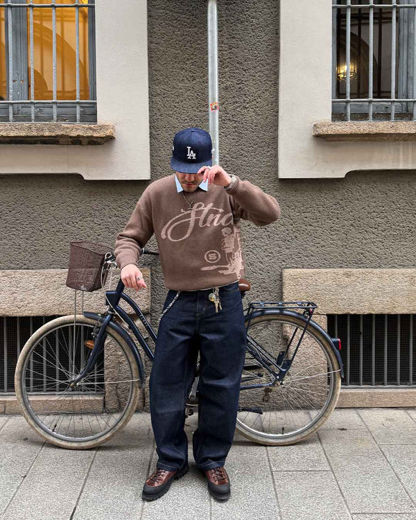 With a bicycle, wearing the Echoes Knit Sweater in brown