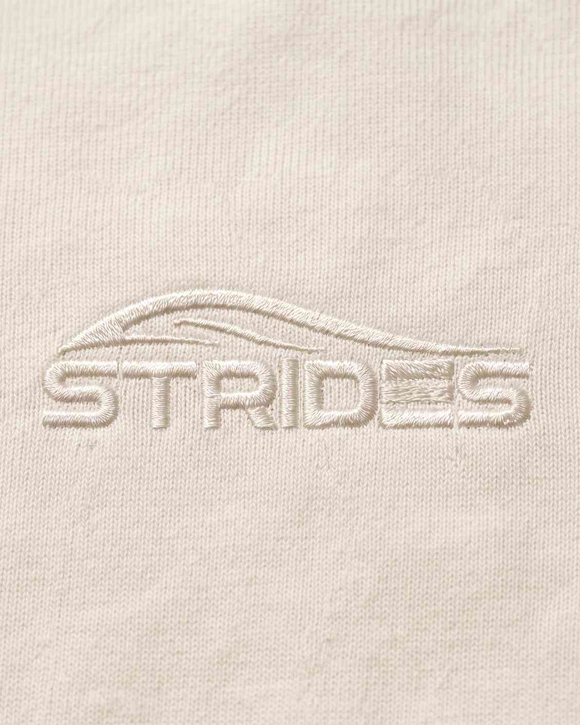 Close-up of the tonal embroidered Strides logo on the white slim tee