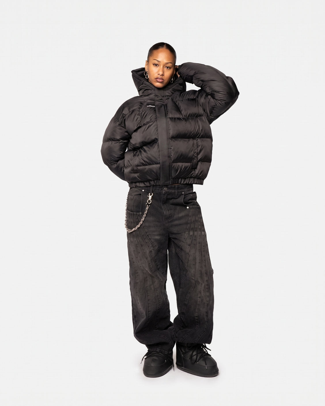 Žena v bundě Apex Puffer Black a černých baggy džínách, pohled zepředu