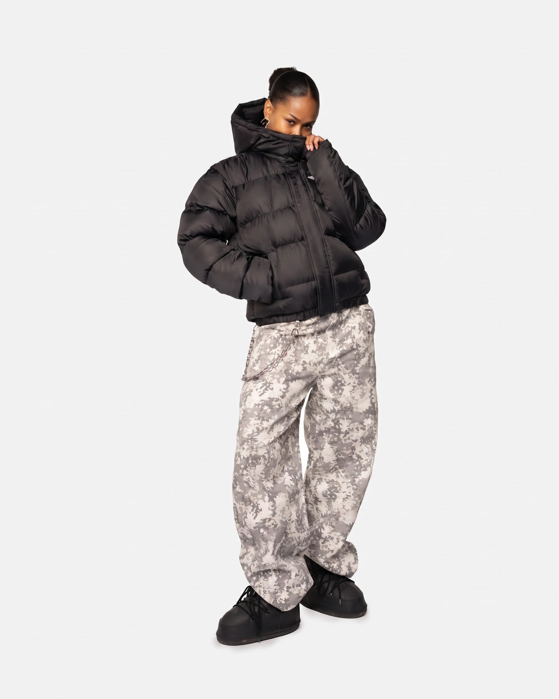 Žena v bundě Apex Puffer Black, kamuflážních kalhotách a sněhulích